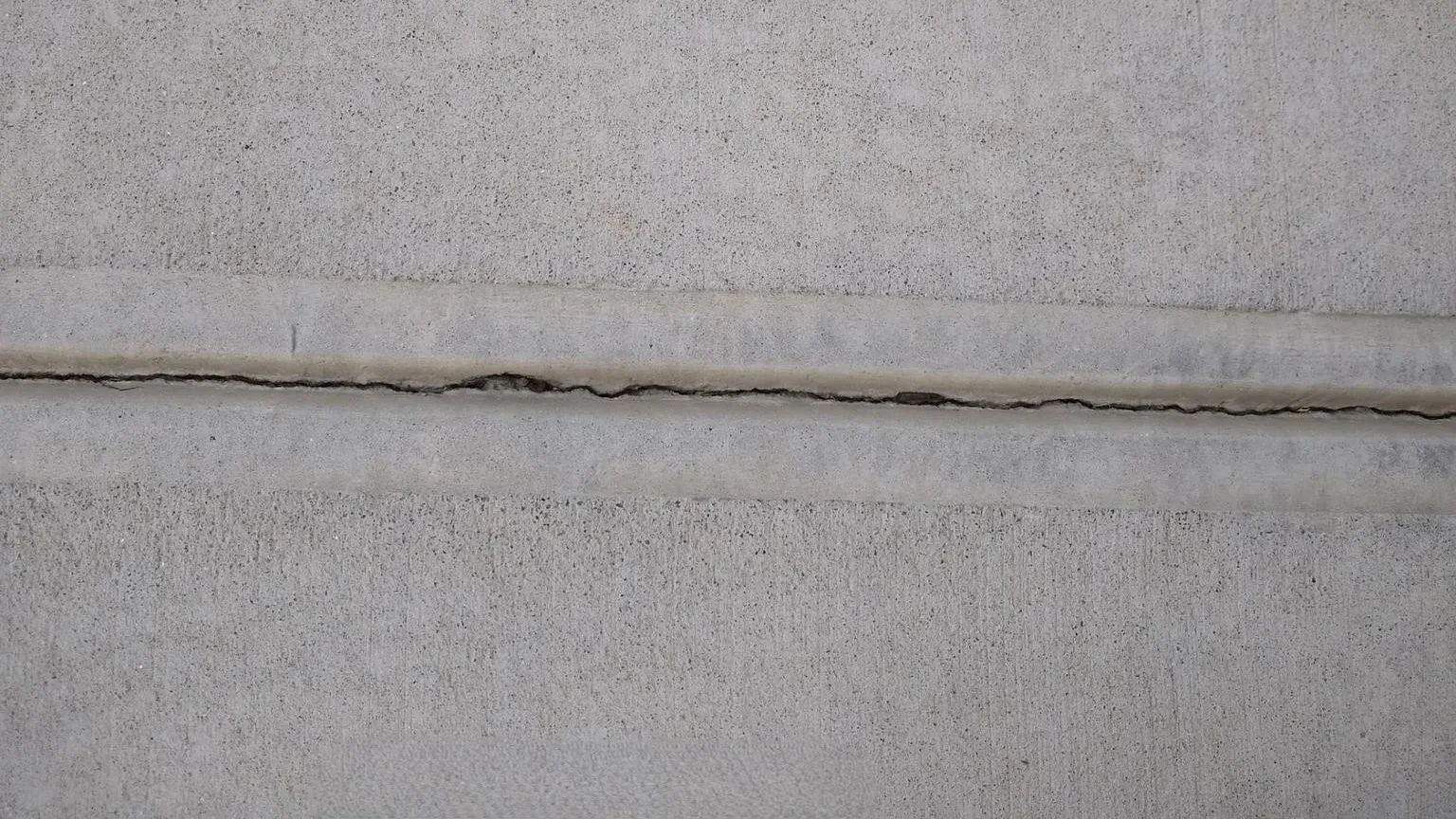 Concrete slab with control joints guiding internal cracks in the surface.