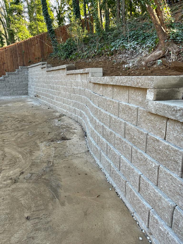 Finished stone retaining wall with integrated drainage line